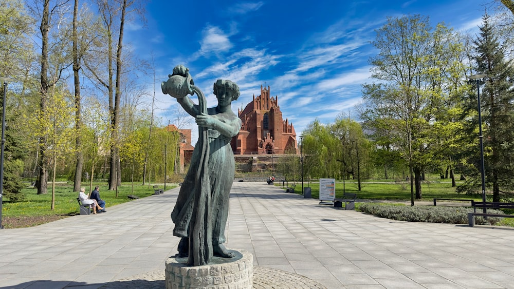 a statue of a woman holding a bird in a park