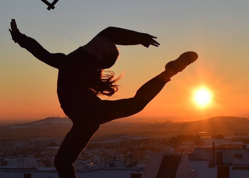 une personne faisant un trick sur une planche à roulettes devant un coucher de soleil