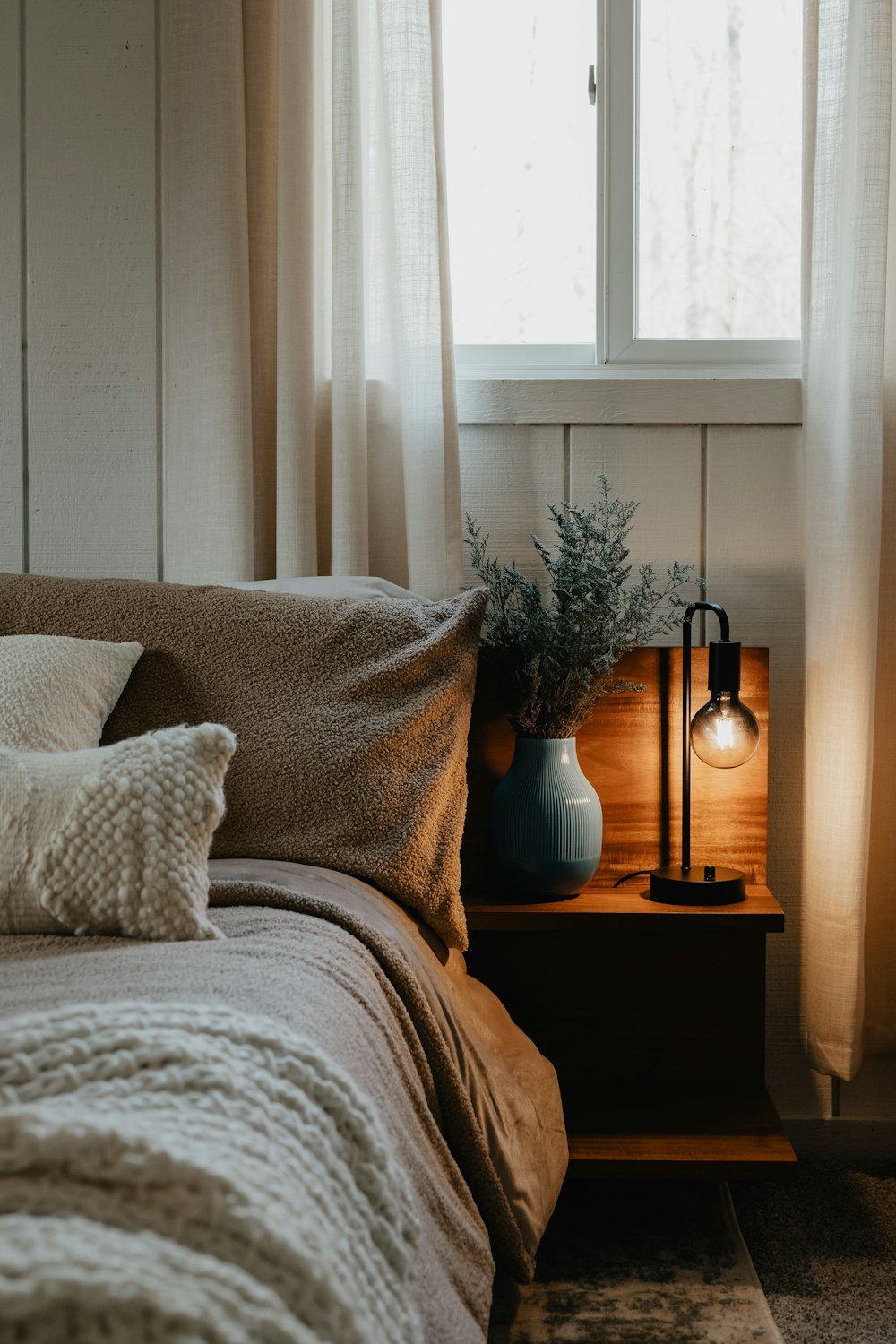 a bedroom with a bed and a nightstand with a lamp on it