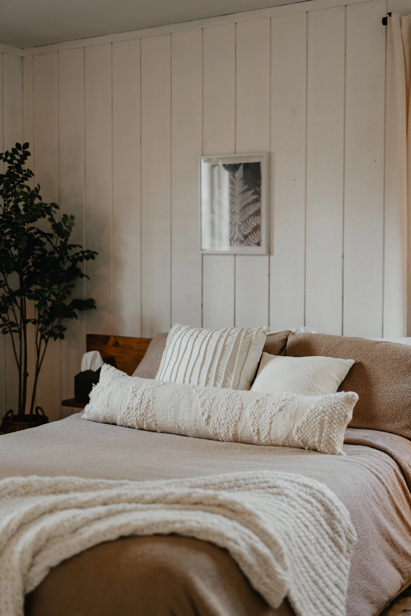 Stylish bed layered with blanket pillows and decorative throw