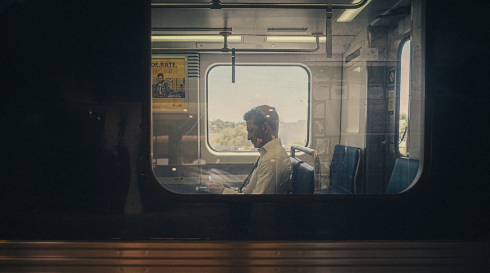 a man sitting on a train looking out the window