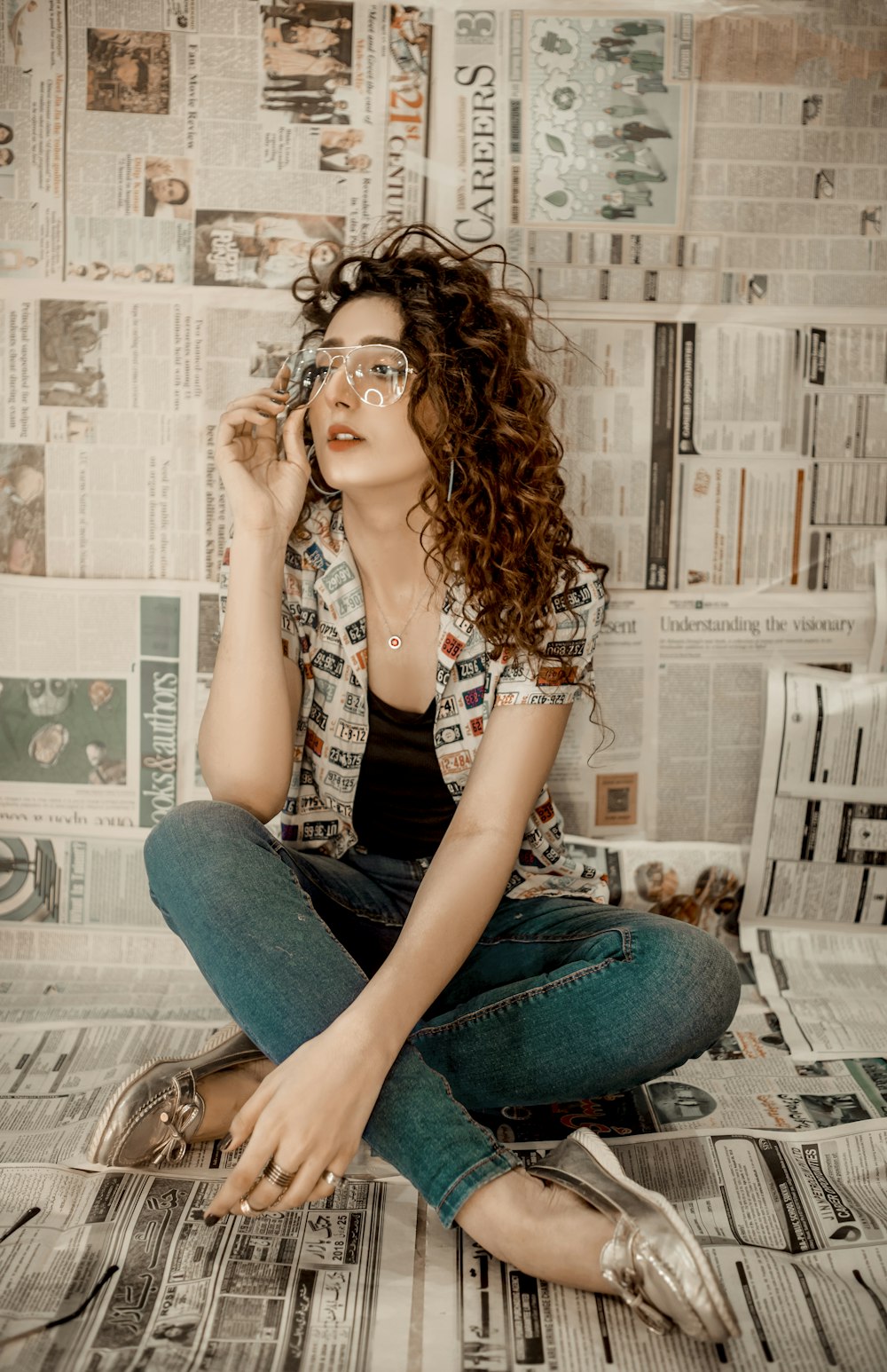 a woman sitting on top of a newspaper covered floor