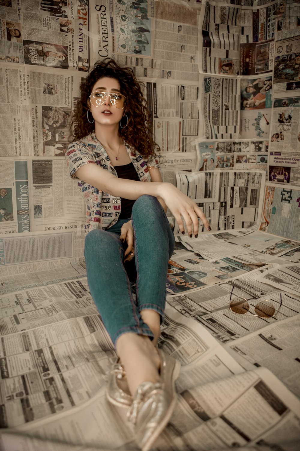 a woman sitting on top of a pile of newspapers