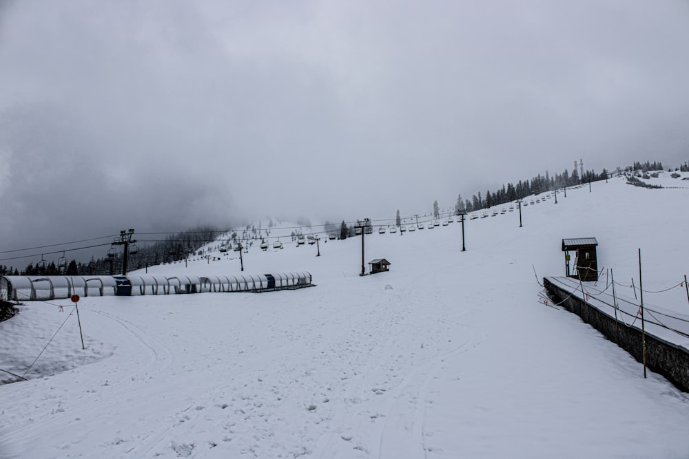 a snow covered ski slope with a ski lift in the distance