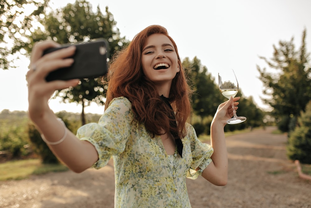 a woman taking a picture of herself with a wine glass