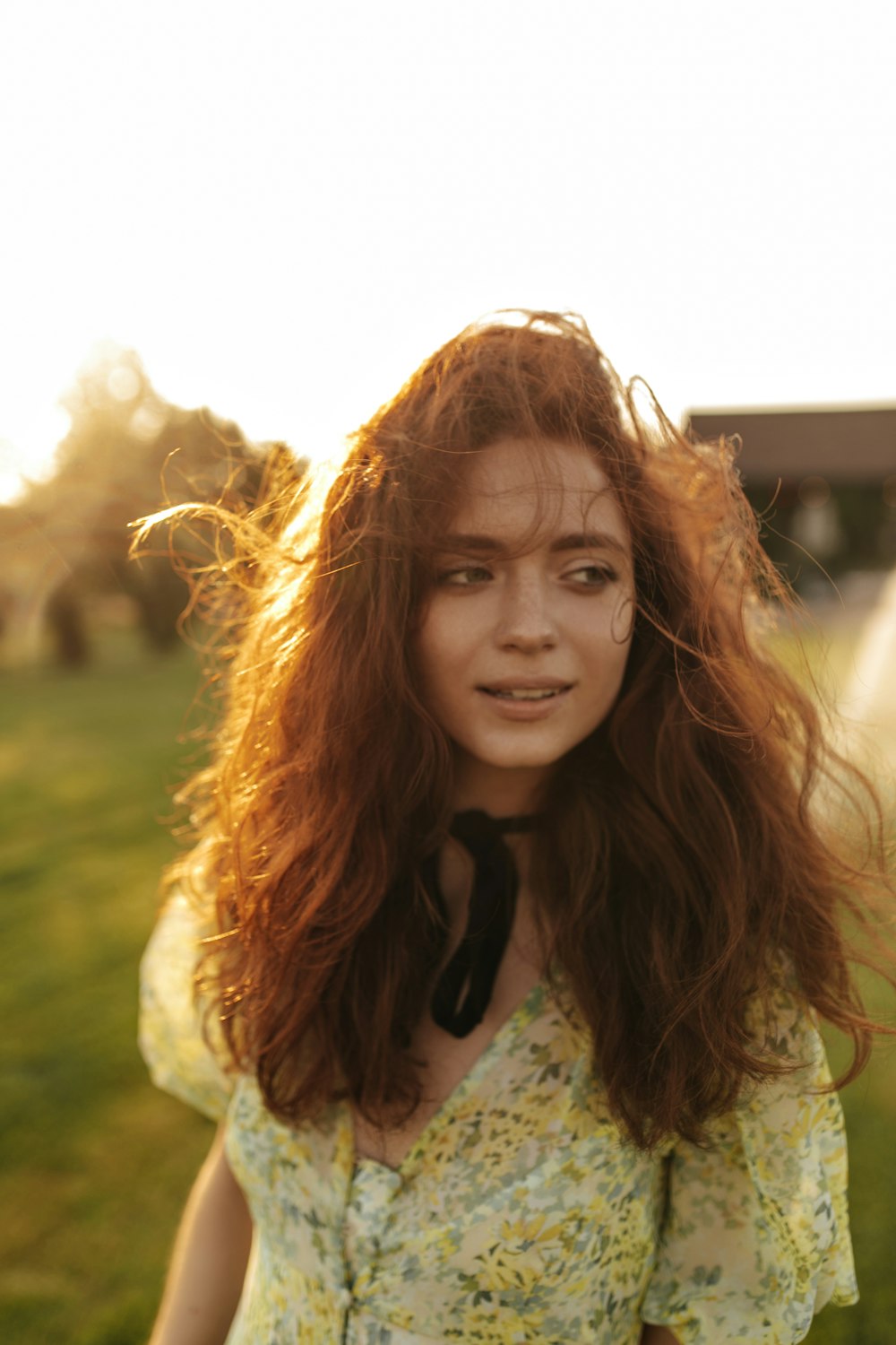 a woman with long red hair standing in a field