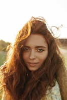 a woman with long hair standing in a field