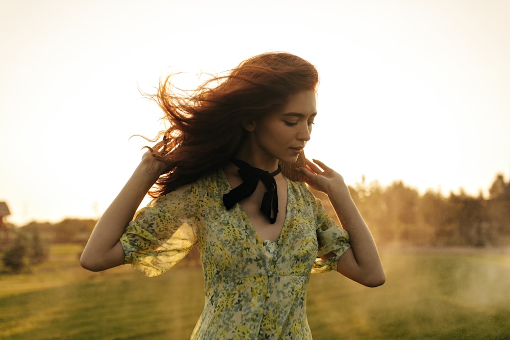 a woman standing in a field with her hair blowing in the wind
