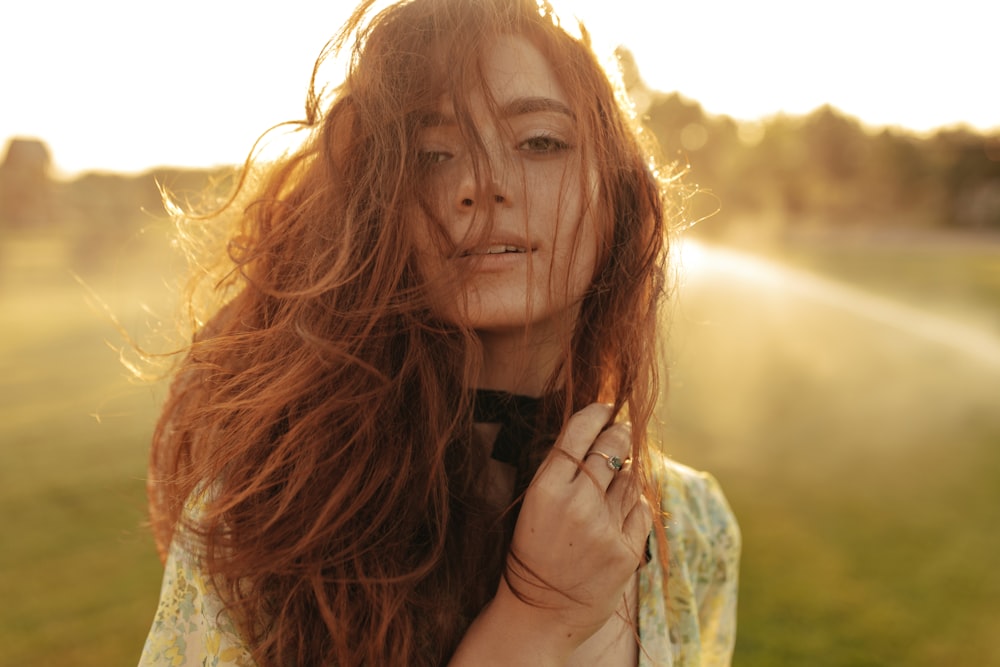 a woman with long red hair standing in a field