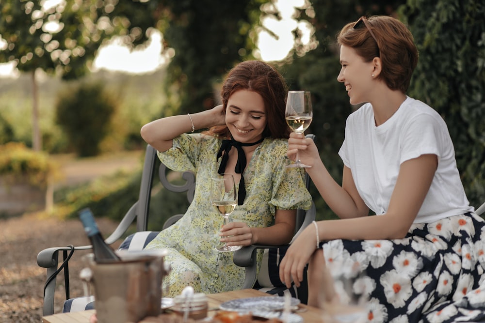 a couple of women sitting next to each other holding wine glasses
