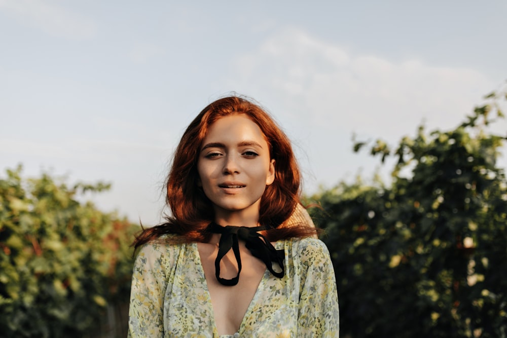 a woman with red hair and a black bow around her neck