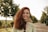 a woman with red hair is smiling and holding a wine glass