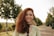 a woman with red hair is smiling and holding a wine glass