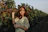 a woman standing in a field holding onto a tree