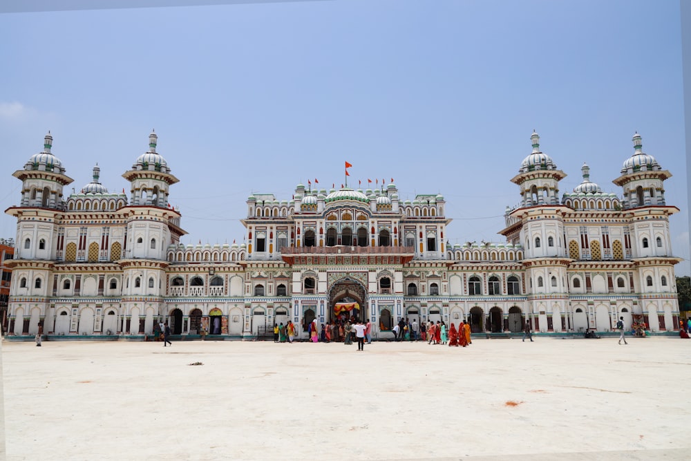 a large white building with lots of people standing in front of it