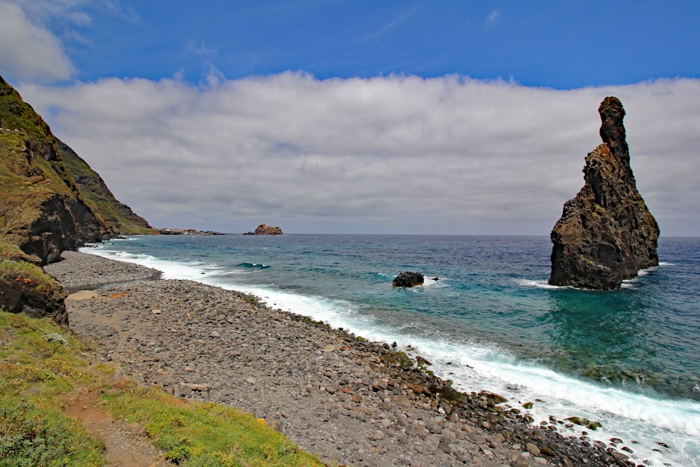 una gran roca que sobresale del océano junto a una playa