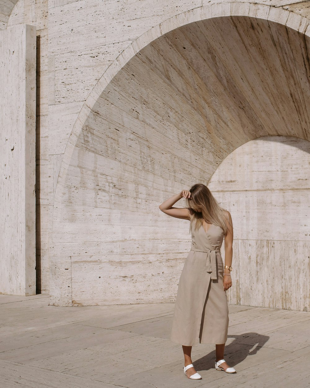 a woman standing in front of a stone arch