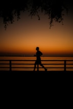 a person running on a bridge at sunset