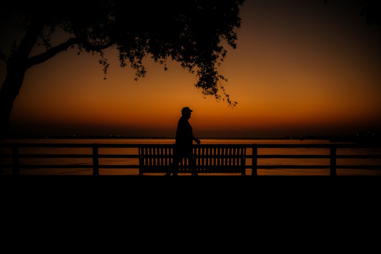 a person standing on a bench near a body of water