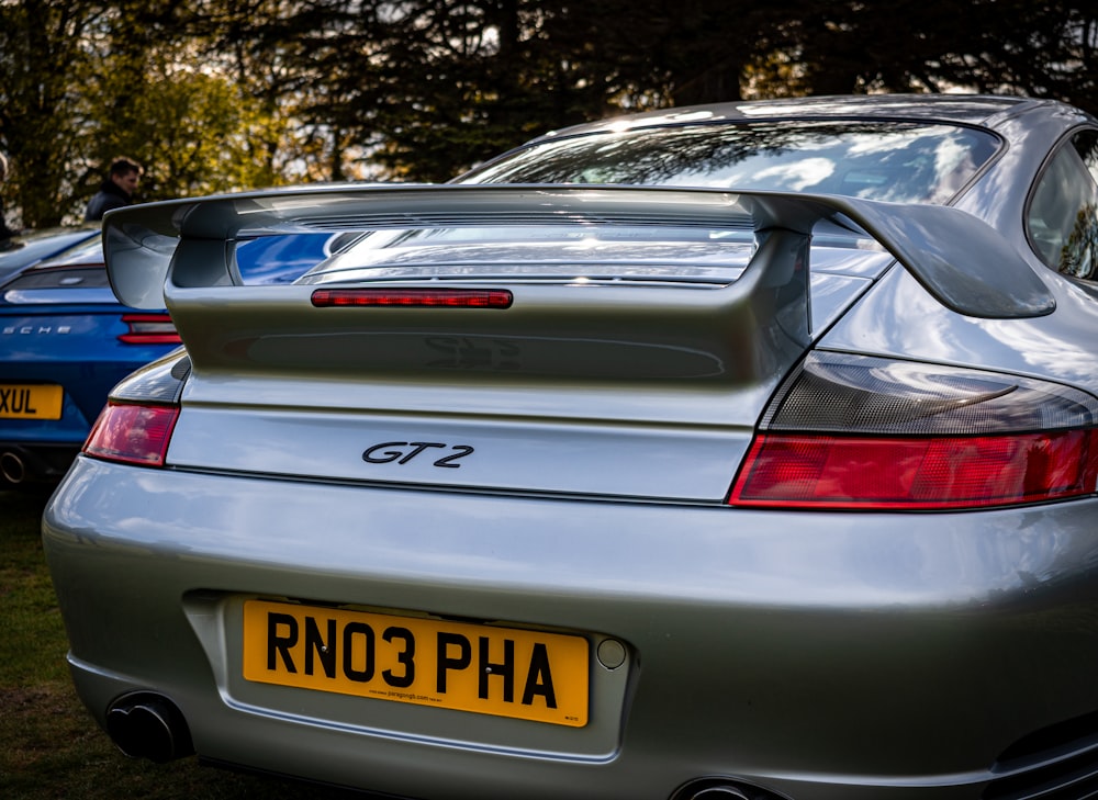 the back of a silver sports car parked in a field