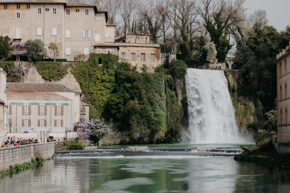 a waterfall in the middle of a river surrounded by buildings