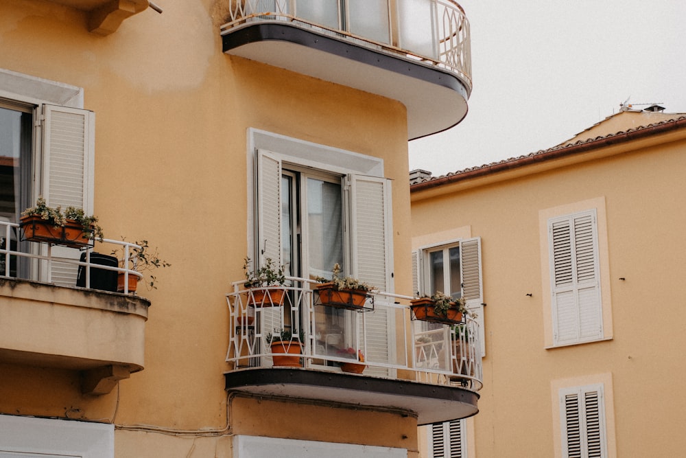 a building with two balconies and a balcony with potted plants