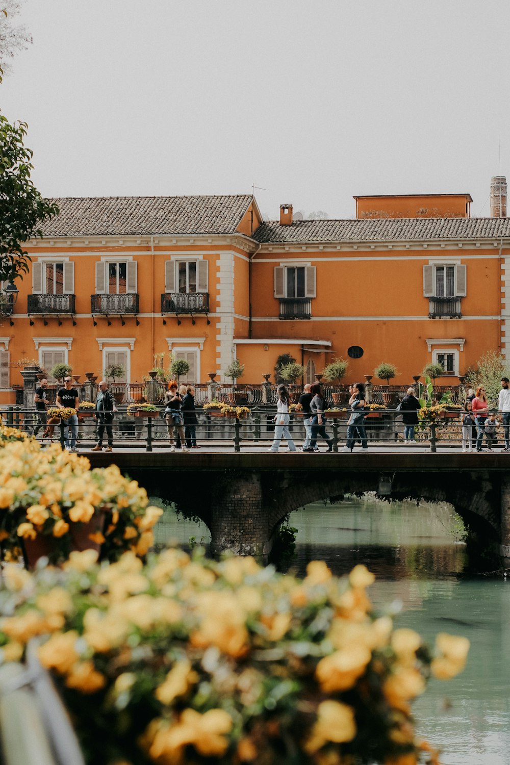 a group of people walking across a bridge over a river