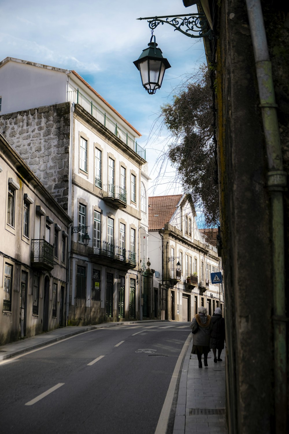 a couple of people walking down a street next to tall buildings