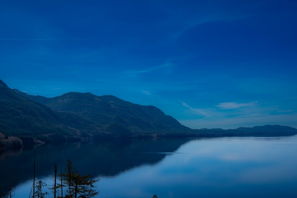 a body of water surrounded by mountains under a blue sky