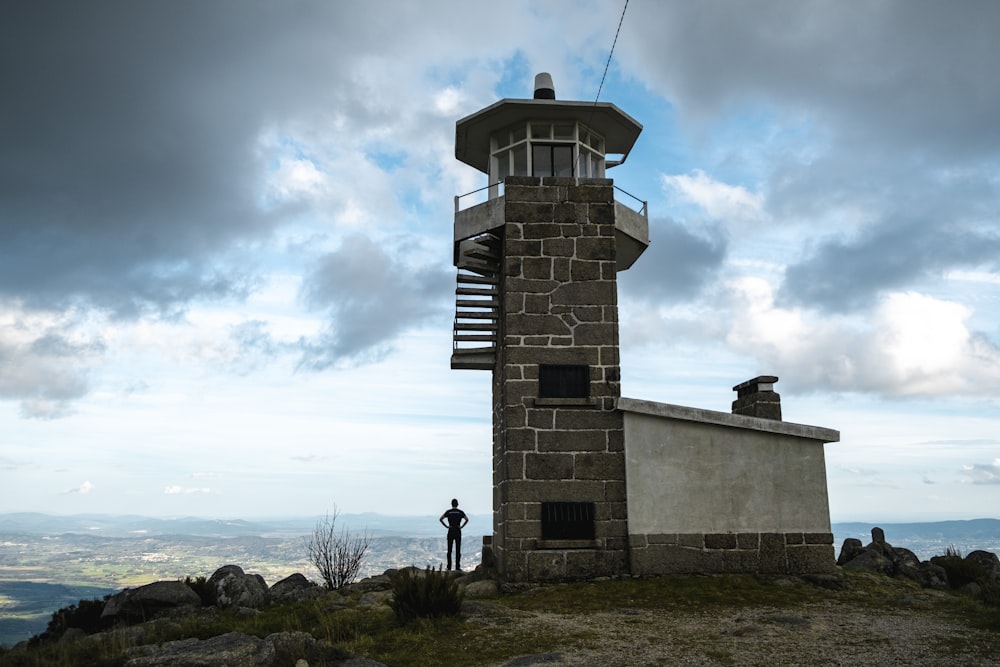 a man standing on top of a hill next to a tower