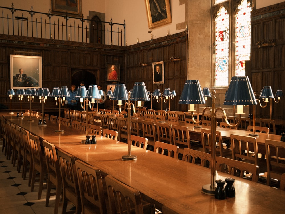 a long table with many chairs and lamps on it