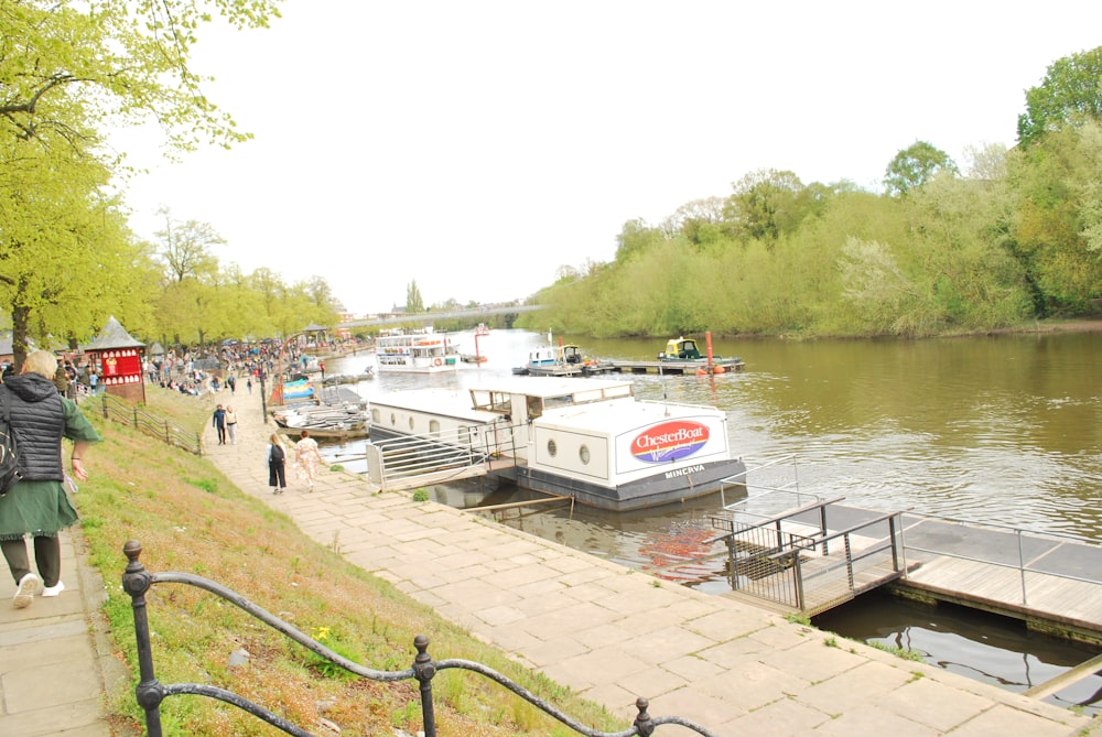 a group of people walking down a sidewalk next to a river