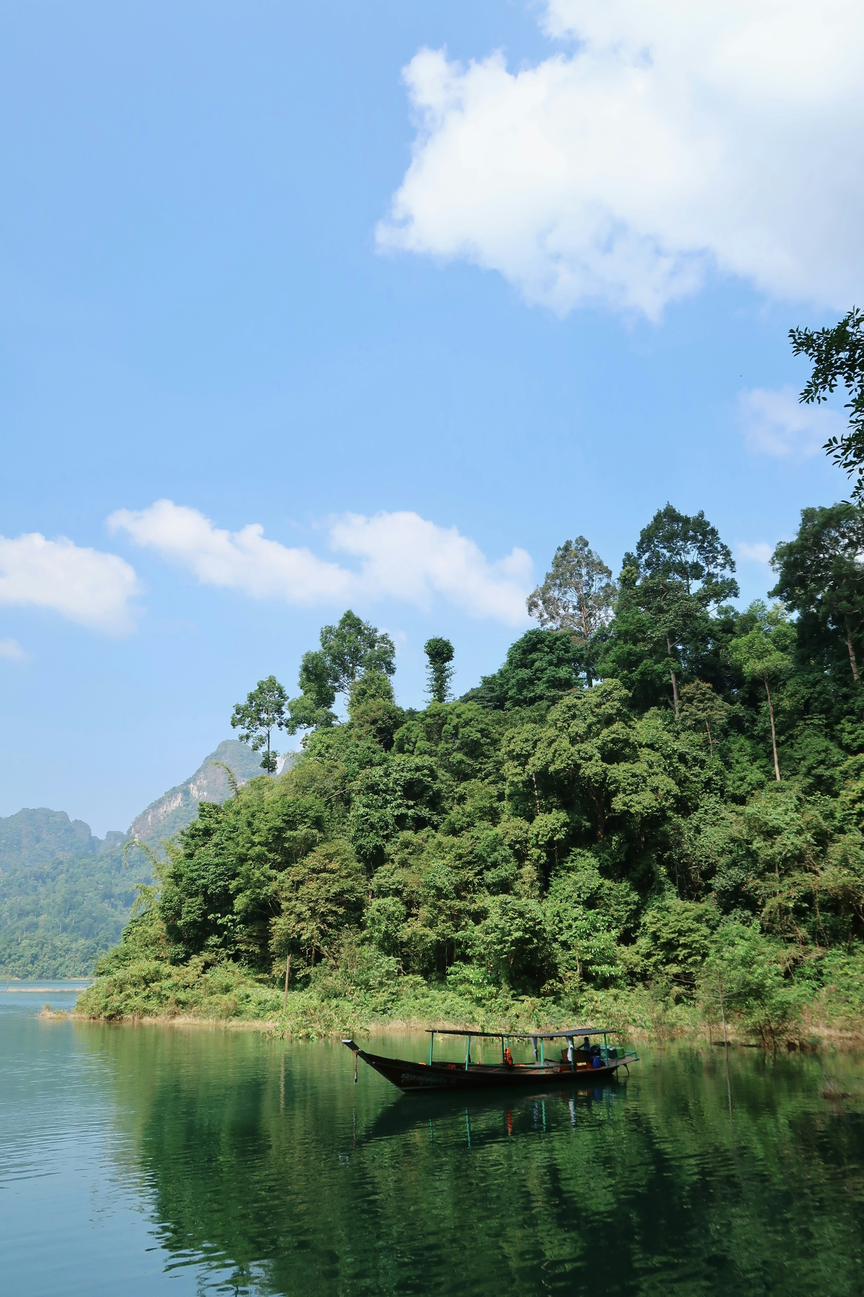 a boat floating on top of a lake surrounded by forest