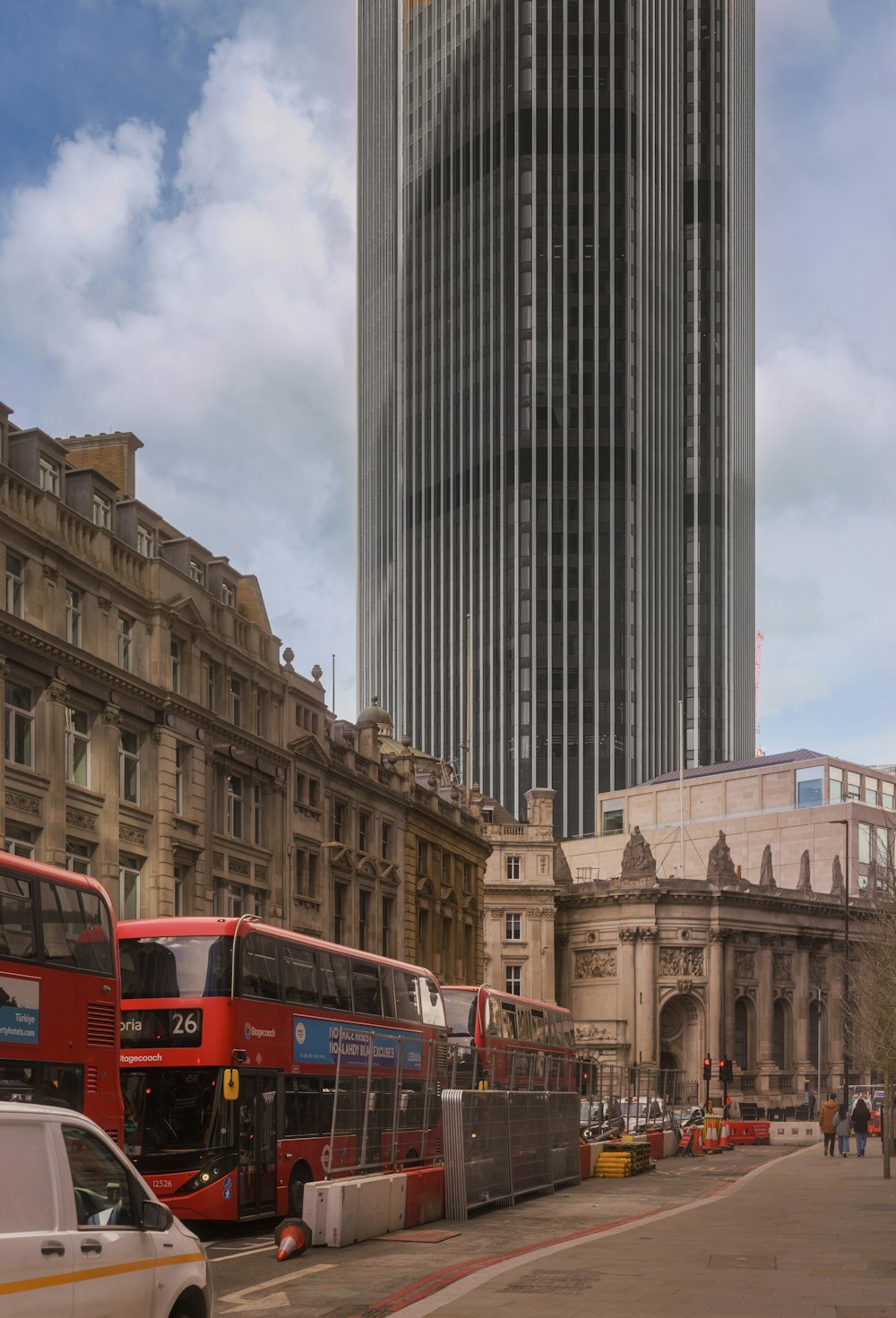 two double decker buses parked in front of a tall building