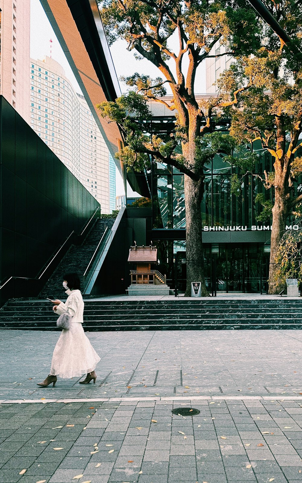 a woman in a white dress is walking down the street