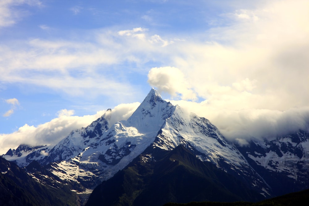 uma grande montanha coberta de neve sob um céu azul nublado