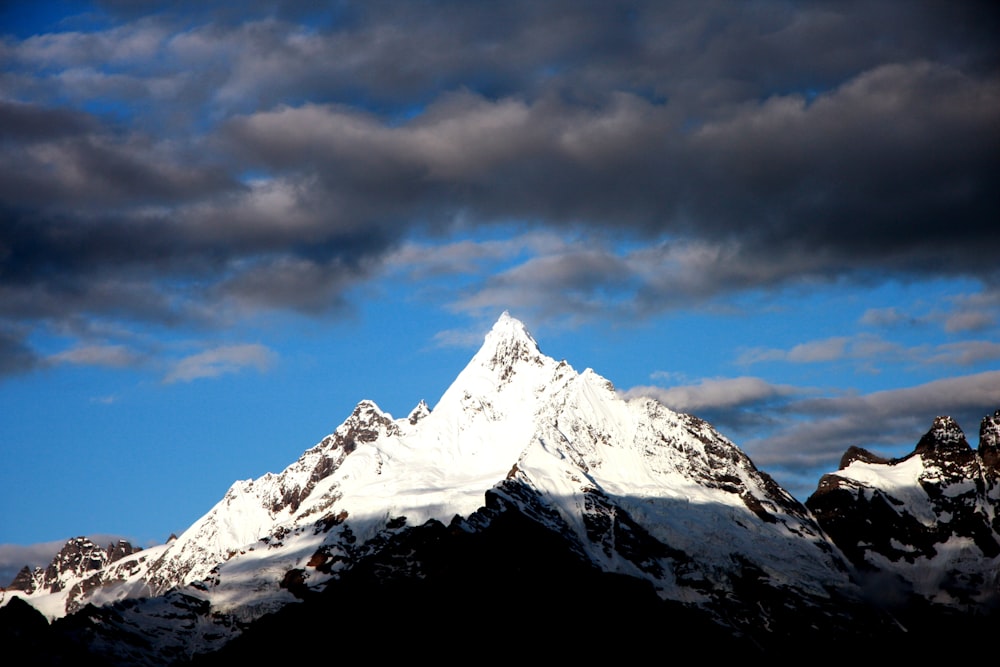 uma montanha coberta de neve sob um céu azul nublado