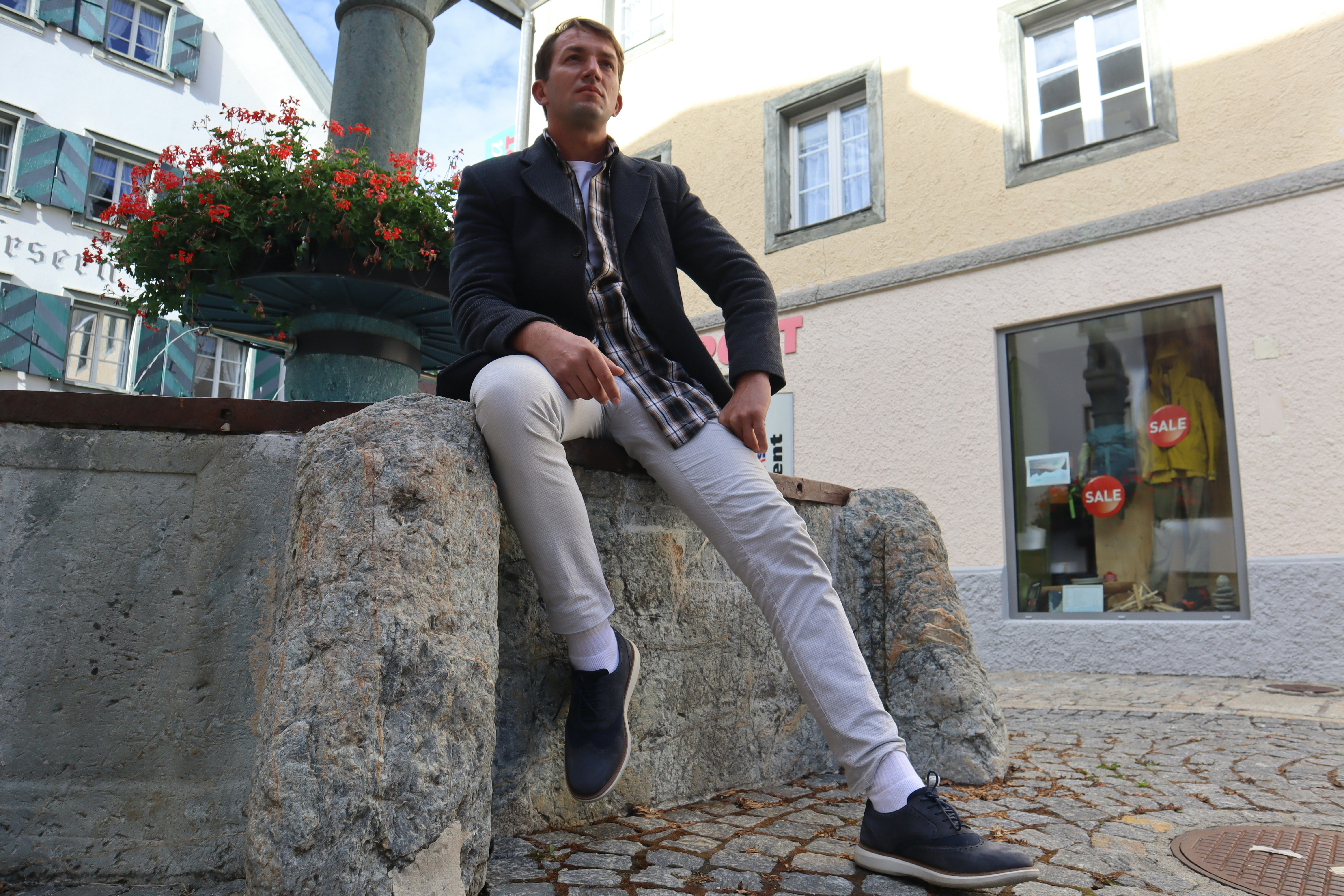 a man sitting on a stone wall in front of a building