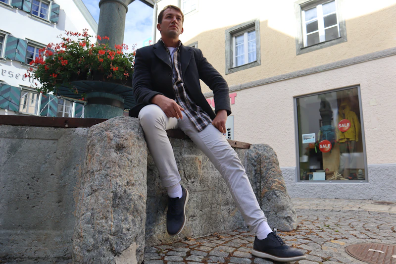 mature man sitting on a stone wall by a building