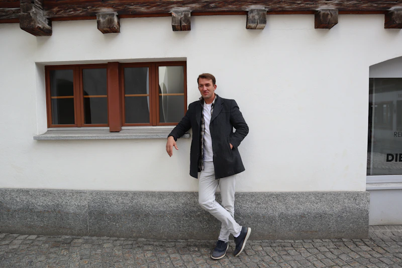 man leaning casually against wall of historic building