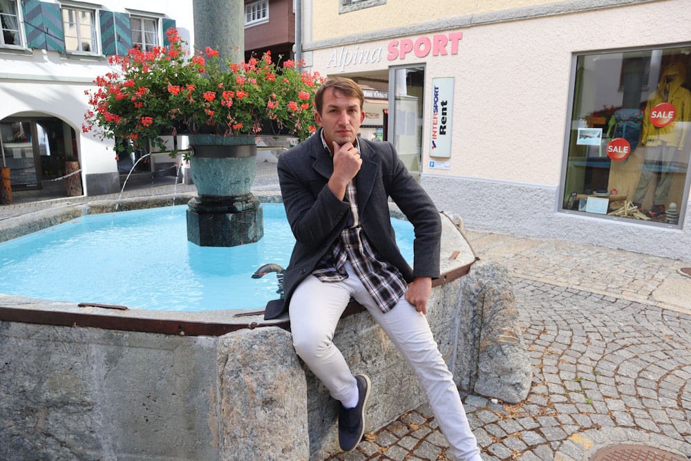 a man sitting on a stone wall next to a fountain