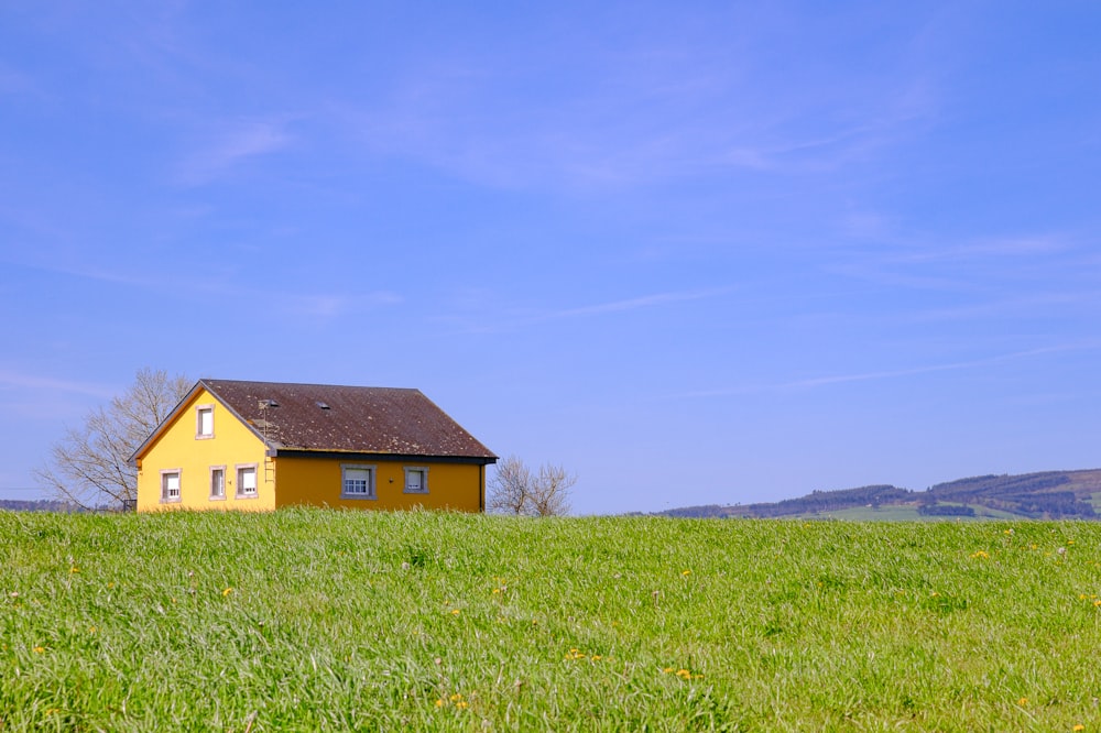 a yellow house sitting on top of a lush green field