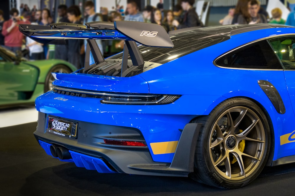 a blue sports car parked in front of a crowd of people