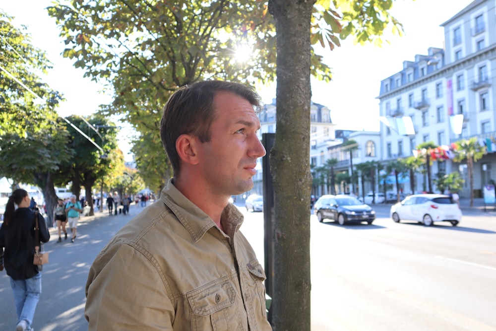 a man standing next to a tree on a city street