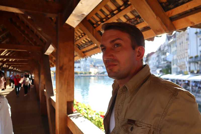 a man standing in front of a building next to a body of water
