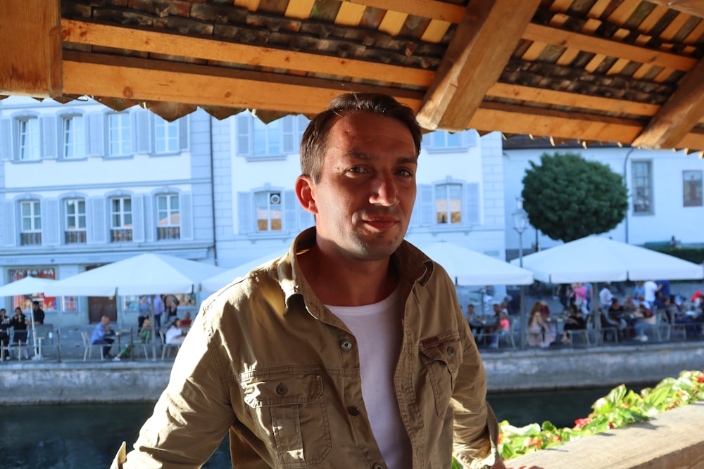 a man standing under a wooden roof next to a river