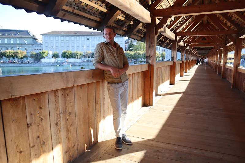 a man standing on a wooden walkway next to a body of water