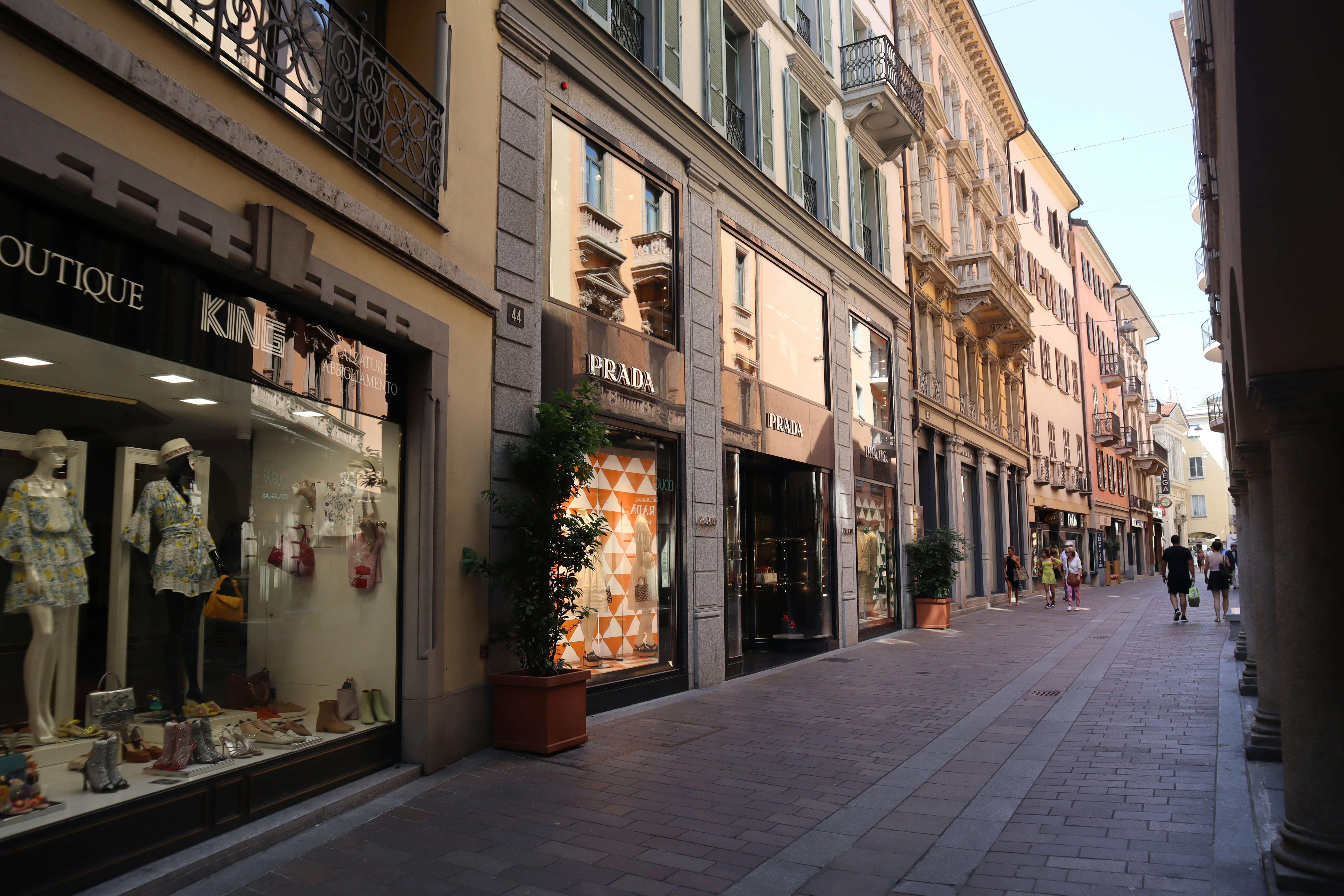 Pedestrians walk along a European street lined with luxury boutiques.