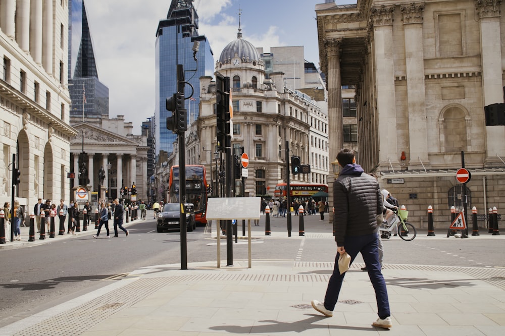 a man walking down a street next to tall buildings