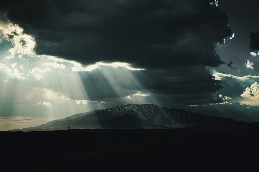 the sun shines through the clouds over a mountain